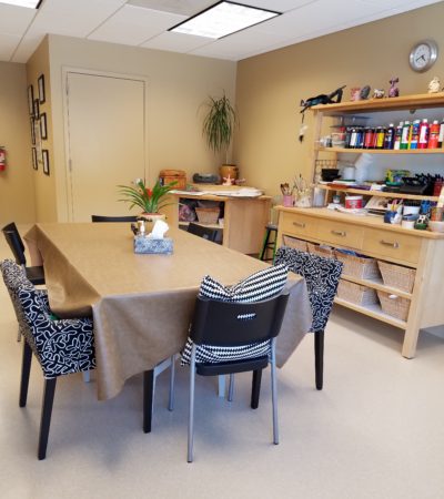 A room with a table and chairs, a desk and a bookshelf.